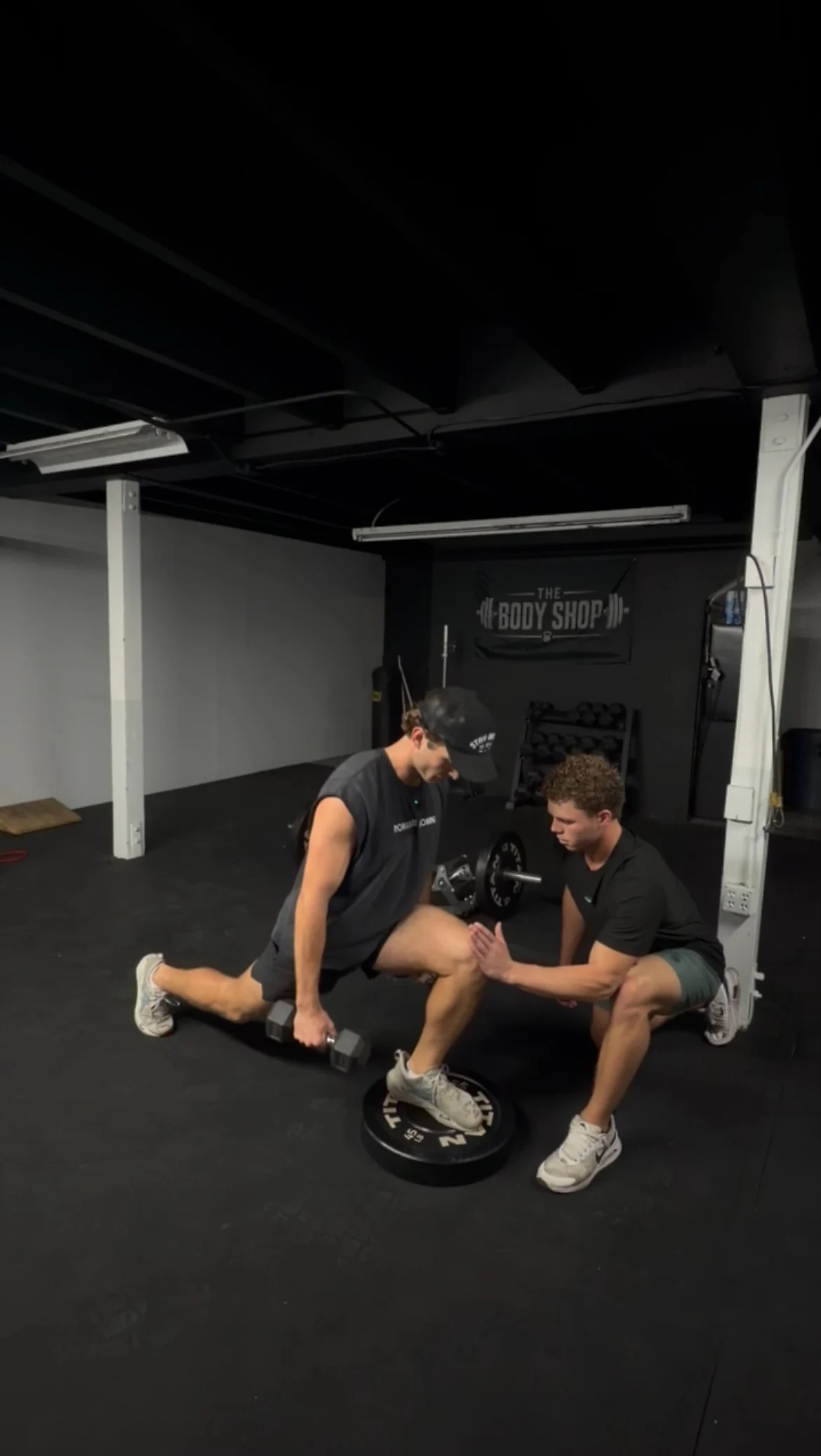 Jarrod Hocking kneeling beside an athlete to coach his position during a split squat