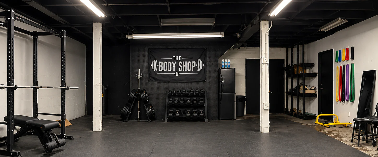 The Body Shop strength room with racks, dumbbells, and the logo banner